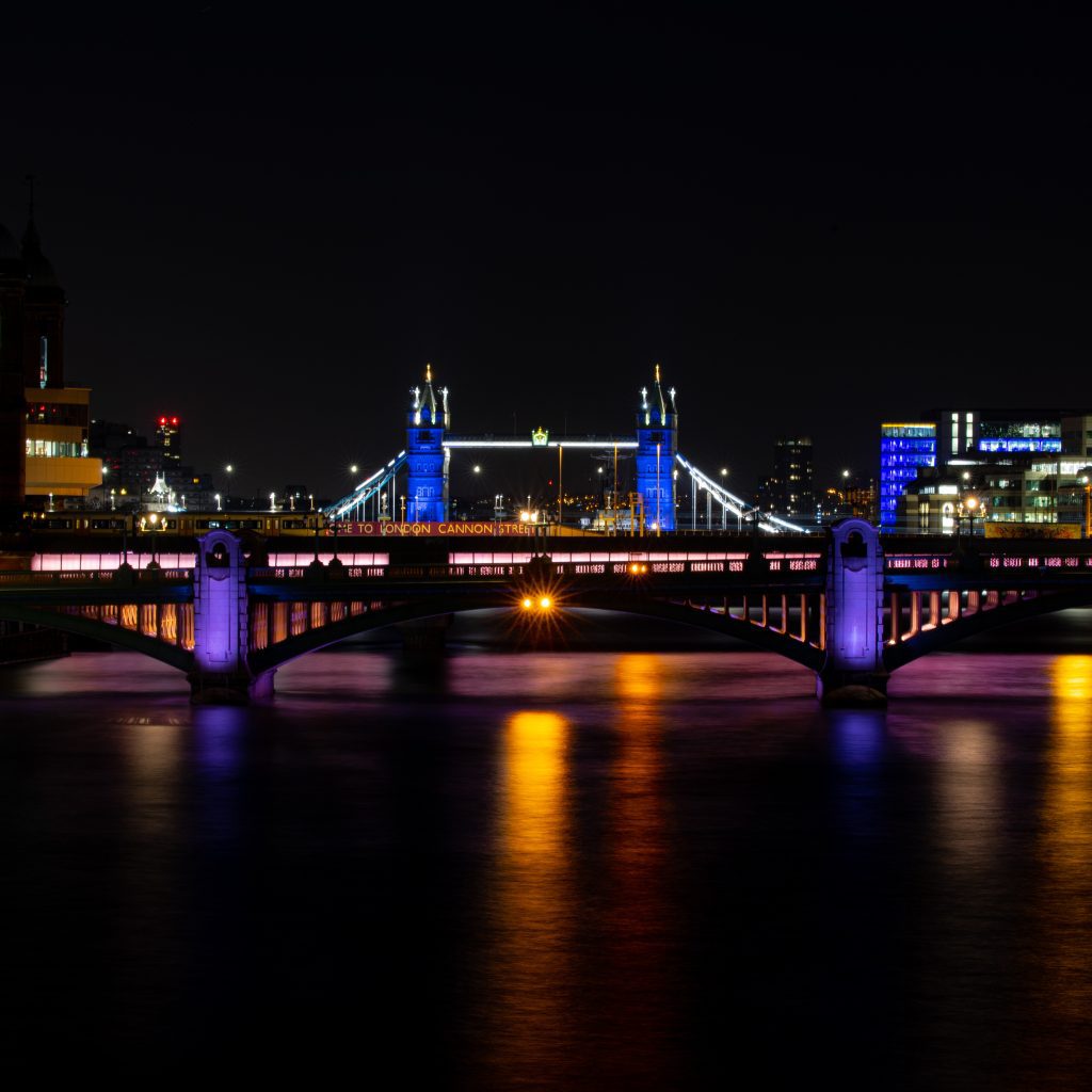 Illuminated Tower Bridge at night reflecting on the River Thames
